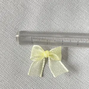 Pale yellow organza mini ribbon bow accessory for DIY crafts shown with scale ruler