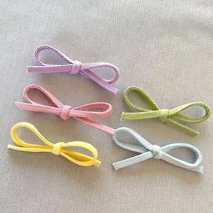 Dettaglio di cinque piccoli fiocchi in tessuto fatti a mano in twill di cotone pastello