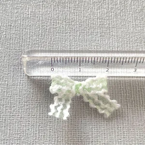Macro view of a 2.5cm mint green handmade lace bow accessory with size ruler detail