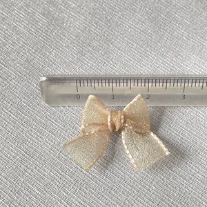 Detailed macro view of a 2.5cm champagne gold organza bow charm with scale measurement
