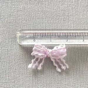 Macro detail of 25mm light purple mesh bow accessory with white scalloped lace edges