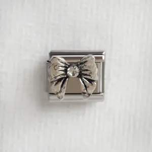 Détail du charm italien en acier inoxydable avec nœud vintage et strass étincelant