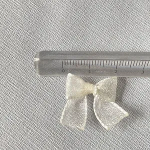 Close-up of cream mesh bow accessory with measuring ruler showing 30mm width detail