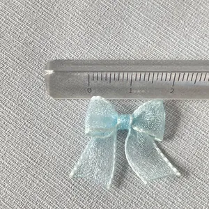 Close-up of 2.5cm light blue organza ribbon bow with delicate metallic edge stitching