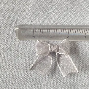 Close-up of a 2.5cm silver organza mini bow accessory with a ruler for size measurement