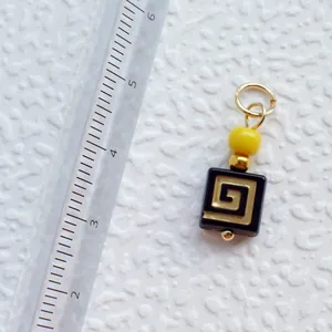 Detailansicht eines handgefertigten Acryl-Anhängers mit Goldmuster neben einem Lineal