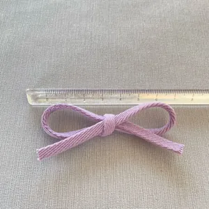 Dettaglio di un fiocco in tessuto viola fatto a mano con un righello per scala di 8cm