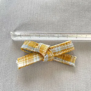 Macro detail of a 7.5cm yellow and blue plaid bow with white stitching for DIY crafts