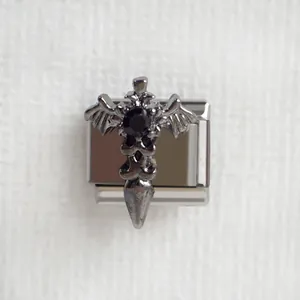 Détail macro du charm gothique ailes de chauve-souris et croix en acier inoxydable noir mat