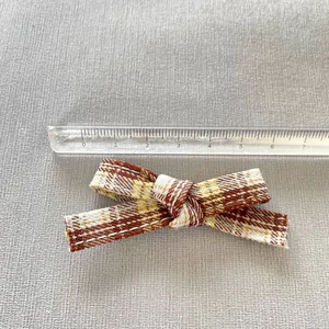 Detail shot of a 7.2cm plaid ribbon bow for DIY doll clothes with a measuring ruler