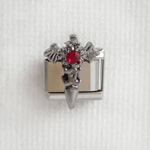 Détail macro du charm italien avec croix gothique, ailes et strass rouge étincelant