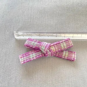 Detail view of a purple plaid bow accessory measured with a ruler showing 7cm length