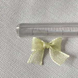 Close-up of 2.5cm mini organza bow accessory with ruler showing precise size details