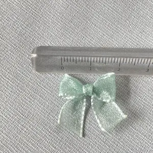 Close-up of a 2cm mint green organza bow with pearl finish for DIY nail art and crafts