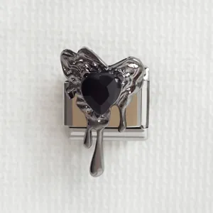 Vue macro d'un charm en acier avec pierre précieuse cœur noir et design en métal fluide