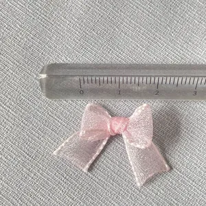 Close-up of a 3cm pink organza mini bow accessory showing fine mesh texture and size scale