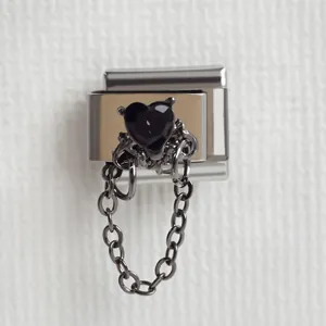 Détail macro du charm italien avec pierre cœur noire et frange de chaîne gothique