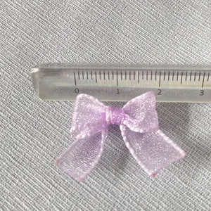 Detailed view of a 2.5cm light purple organza bow with fine edging on textured fabric