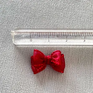 Macro shot of a 3cm mini red organza ribbon bow measured with a clear scale ruler