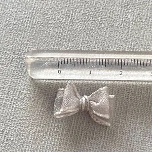 Close-up of a 2.5cm silver-gray mesh bow accessory showing fine metallic weave texture