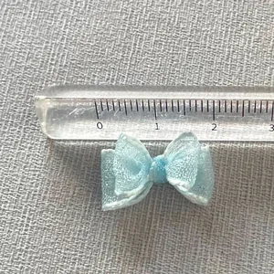 Close-up of a 2.5cm light blue organza ribbon bow accessory with measurement ruler