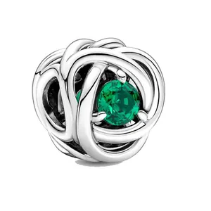 Dettaglio charm in argento con design intrecciato e pietra portafortuna verde incastonata