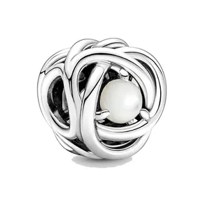 Dettaglio macro dello charm a nodo cavo in lega con perla bianca incastonata