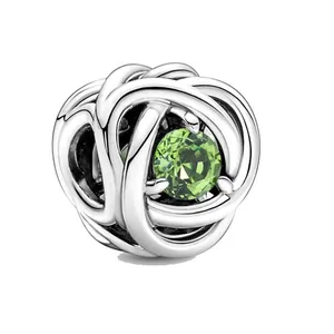 Dettaglio macro dello charm a nodo argento con gemma verde sfaccettata per gioielli DIY