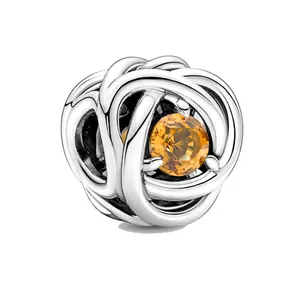 Dettaglio macro dello charm intrecciato argento con pietra portafortuna ambra