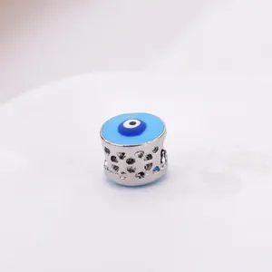 Hollow silver charm bead with blue evil eye enamel pattern on white background