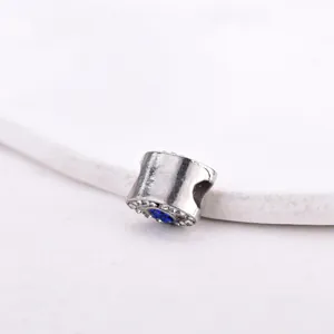 Gros plan d'une perle en argent avec pierre bleue centrale et halo de zircons brillants