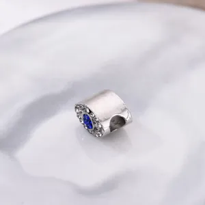 Détail macro du charm œil protecteur argenté avec pierre bleue et cristaux blancs