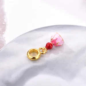 Detail of pink enamel flower and red strawberry charm bead with golden metal ring