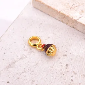 Macro shot of a chocolate cupcake charm with a red cherry detail on a golden base