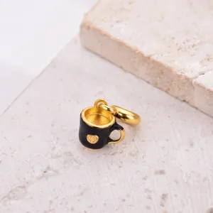 Detailed view of a gold-plated coffee cup charm with black enamel and a heart pattern