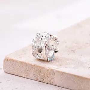 Silver crescent moon charm with sparkling zircon stones on natural stone base