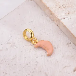 Macro detail of golden croissant charm with light orange enamel for DIY bracelet charms