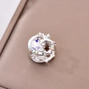 Close-up of a silver moon-shaped charm with a large crescent crystal and colorful accents