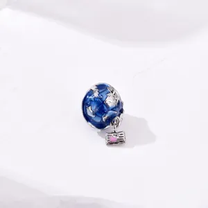 Detailed view of silver globe charm with blue enamel ocean and pink heart suitcase pendant