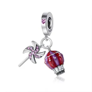 Dettaglio charm in argento S925 con gemma a cuore rosa, mongolfiera e ciondolo a mulino