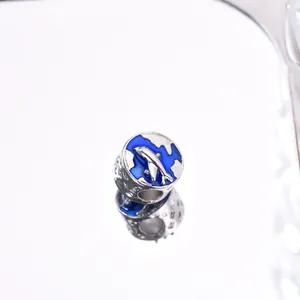 Macro shot of S925 silver airplane and blue enamel globe charm with reflective finish