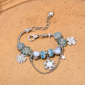 Bracelet à breloques argenté avec perles bleues et flocons de neige sur fond de sable