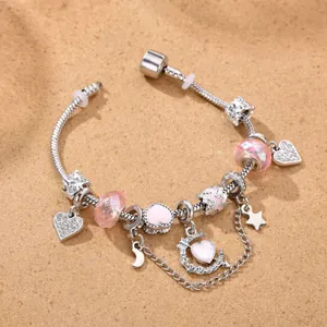 Detalle de cuentas de resina rosa y dijes de luna y corazón en pulsera de cadena de plata