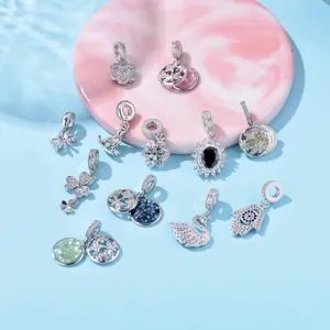 Silver insect and floral zircon charms set displayed on a marble plate over water background