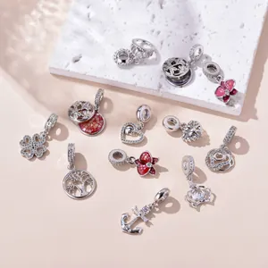 Macro shot of assorted silver charms with zircons and enamel on a white stone background