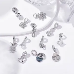 Detailed close-up of zircon snowflake heart charms and owl pendants on white tray