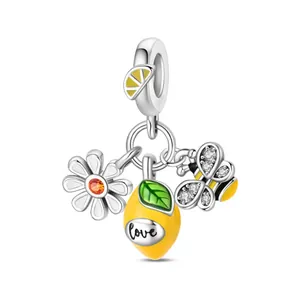 Dettaglio di ciondoli in lega con margherita, limone giallo Love e ape con pavé di diamanti