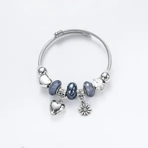 Silver beaded bracelet with blue glass beads, sunflower charm, heart pendant, and clock charm