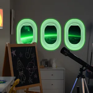 Detailed view of three glow-in-the-dark airplane window wall decals with space scenery