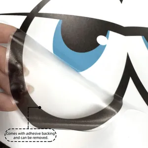 Detail showing cartoon eye sticker with adhesive backing being peeled for application
